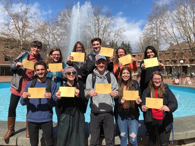 Holocaust and Genocide Studies students holding up declaration cards in front of the Red Square fountain